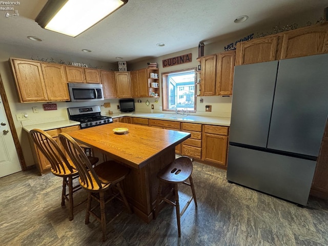 kitchen with a sink, a center island, a breakfast bar, stainless steel appliances, and open shelves