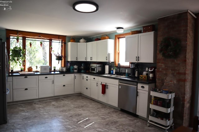 kitchen with a sink, white cabinets, dishwasher, dark countertops, and tasteful backsplash