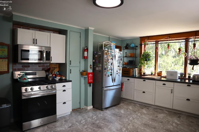 kitchen featuring a sink, stainless steel appliances, crown molding, dark countertops, and marble finish floor