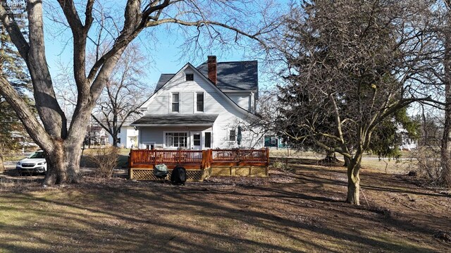 back of house with a lawn, a deck, and a chimney