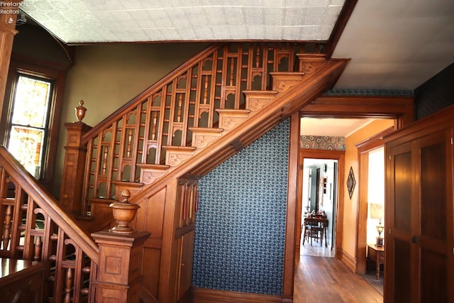 stairs featuring wallpapered walls and wood finished floors