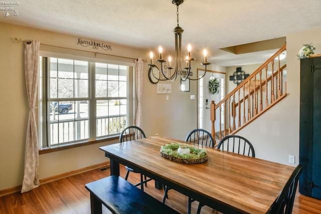 dining room featuring a notable chandelier, wood finished floors, baseboards, and a textured ceiling