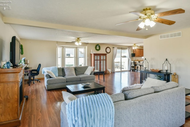 living room featuring visible vents, beamed ceiling, baseboards, and wood finished floors