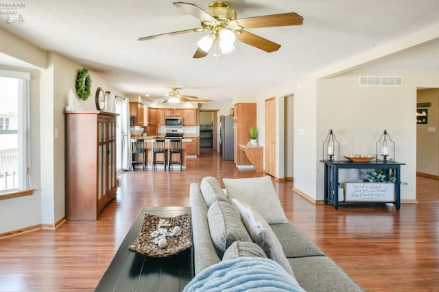 living area featuring light wood-style floors, visible vents, and baseboards