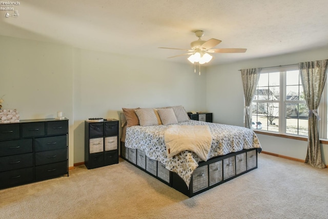 bedroom featuring light colored carpet, a ceiling fan, and baseboards