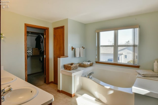 bathroom with a walk in closet, a sink, tile patterned flooring, double vanity, and a bath