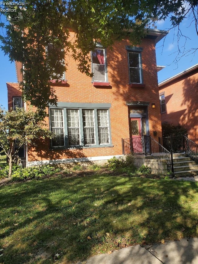 view of front facade featuring brick siding and a front yard