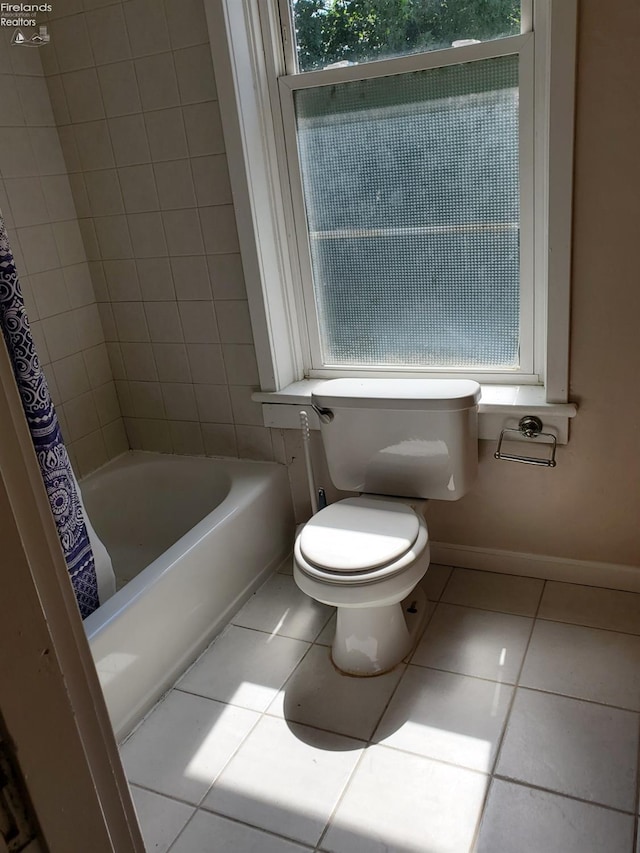 full bath featuring tile patterned floors, toilet, shower / tub combo with curtain, and baseboards