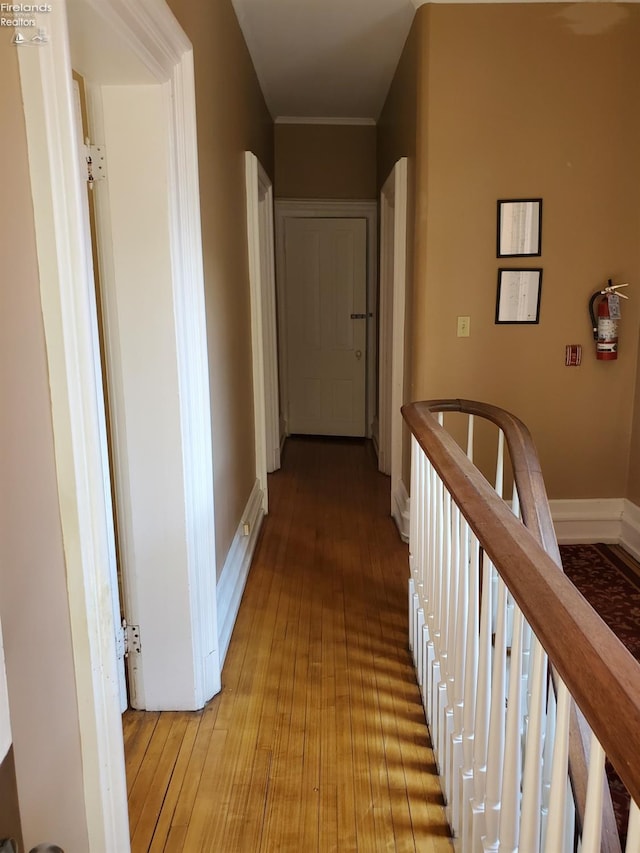 hallway with an upstairs landing, light wood-type flooring, and baseboards