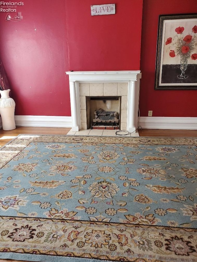 interior space featuring baseboards, wood finished floors, and a tile fireplace