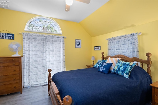 bedroom with a ceiling fan, lofted ceiling, and wood finished floors