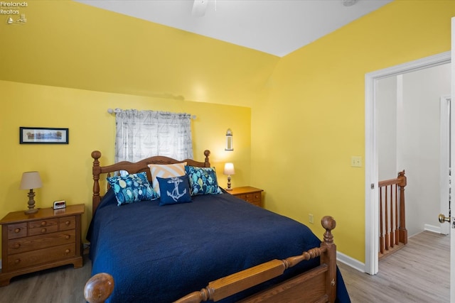 bedroom featuring baseboards, lofted ceiling, wood finished floors, and a ceiling fan