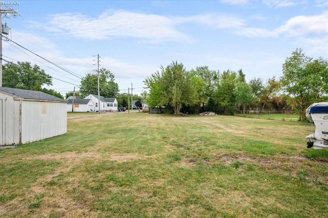 view of yard with an outdoor structure, a storage unit, and fence