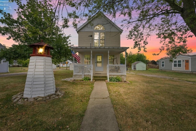 victorian home with a front lawn, an outbuilding, and covered porch