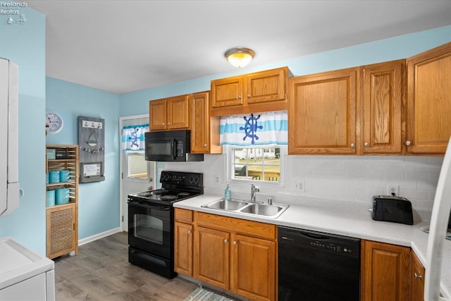 kitchen featuring backsplash, black appliances, light countertops, and a sink