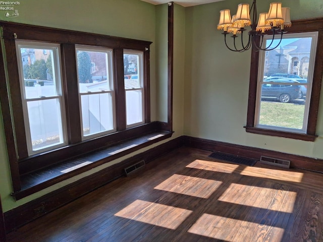 spare room with visible vents, a notable chandelier, and dark wood finished floors