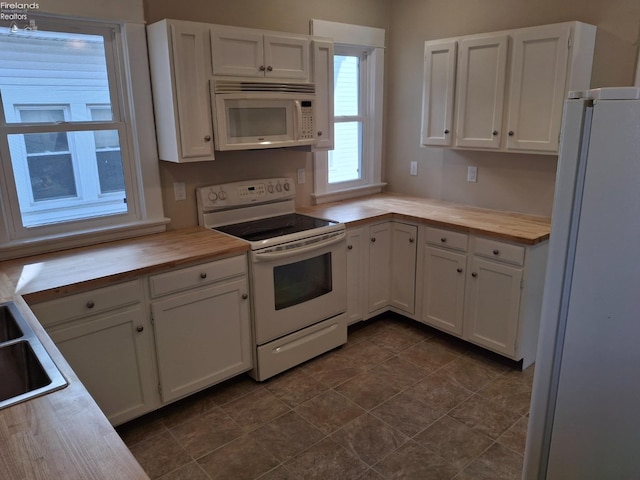 kitchen featuring white appliances, wooden counters, and white cabinets