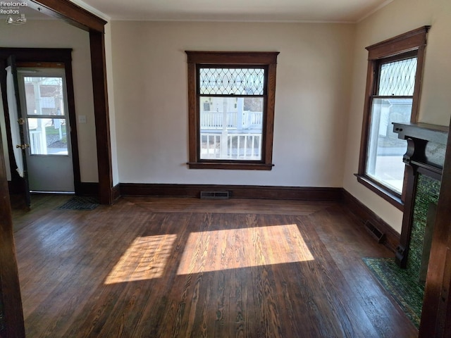 empty room featuring visible vents, baseboards, and wood finished floors