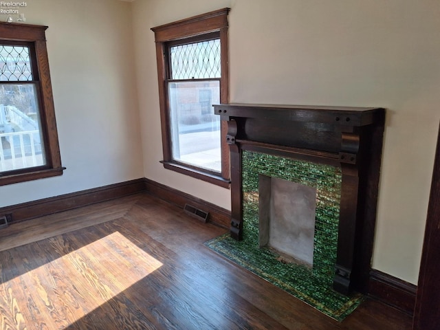 unfurnished living room featuring baseboards, visible vents, and a tile fireplace