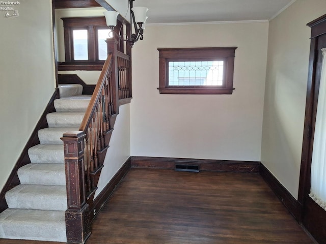 stairway with baseboards, wood finished floors, and ornamental molding