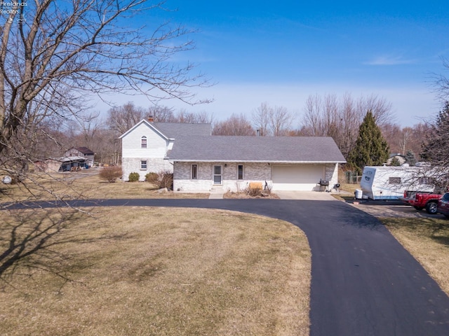 view of front facade with aphalt driveway, a chimney, a front yard, and roof with shingles