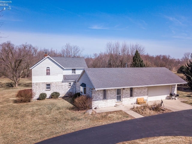 view of front facade with brick siding, a shingled roof, concrete driveway, a chimney, and an attached garage