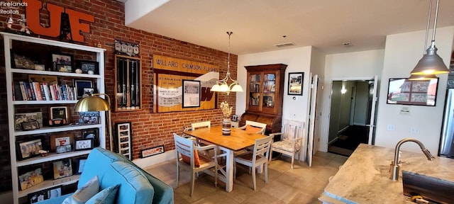 tiled dining area with a notable chandelier, visible vents, brick wall, and a sink