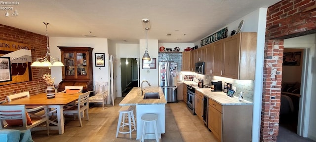 kitchen with decorative light fixtures, brick wall, stainless steel appliances, and light tile patterned flooring