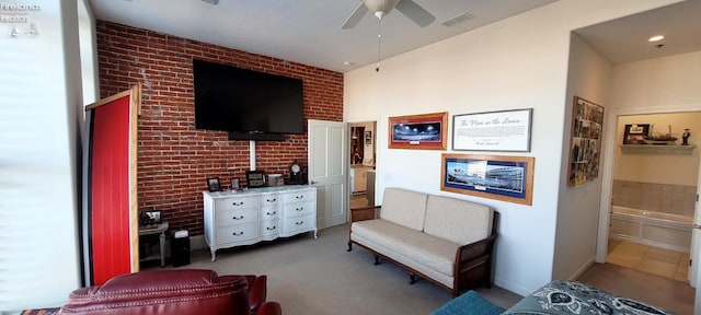 sitting room featuring a ceiling fan, visible vents, and brick wall