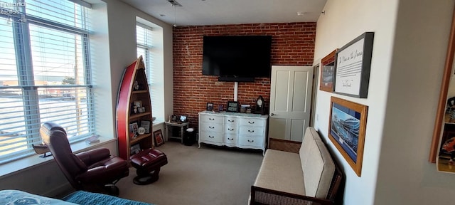 carpeted living room with brick wall