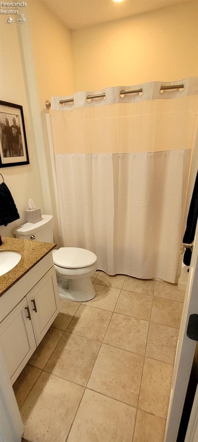 bathroom featuring curtained shower, toilet, vanity, and tile patterned flooring