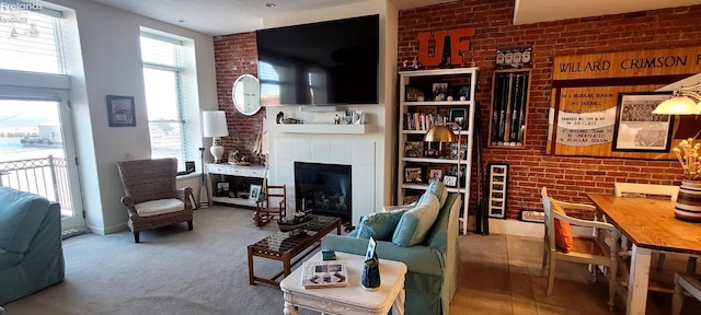 living area featuring a tile fireplace, brick wall, and carpet floors