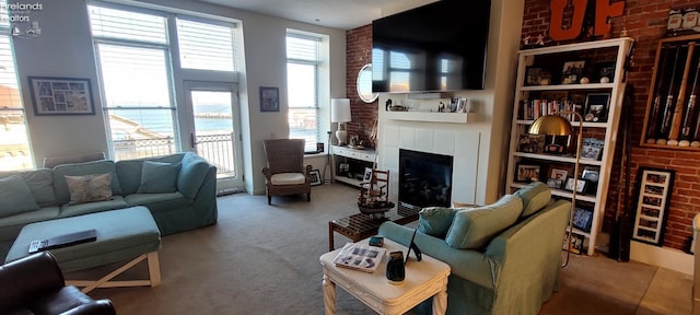 living room featuring brick wall, carpet flooring, and a tile fireplace