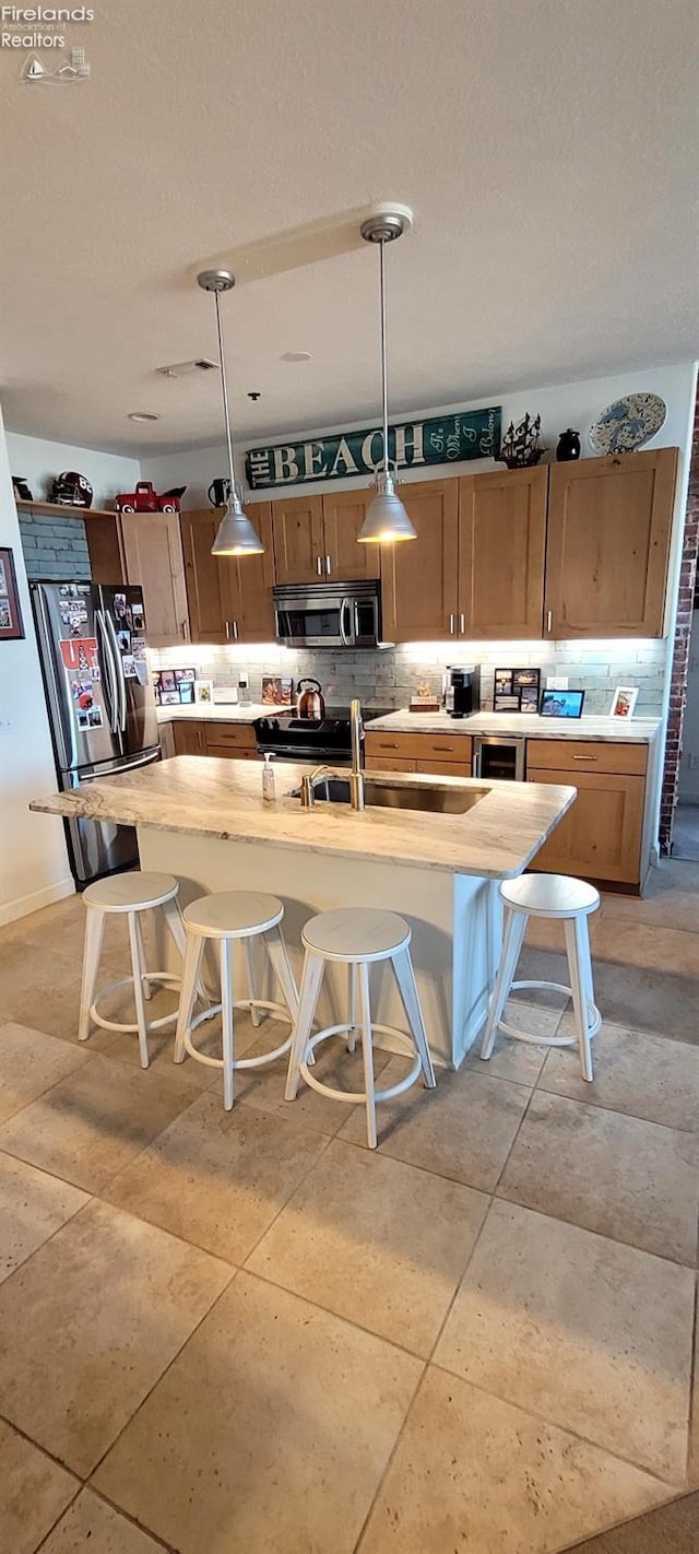 kitchen with pendant lighting, tasteful backsplash, appliances with stainless steel finishes, a breakfast bar area, and light countertops