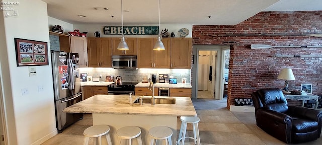 kitchen featuring visible vents, backsplash, brick wall, appliances with stainless steel finishes, and a sink