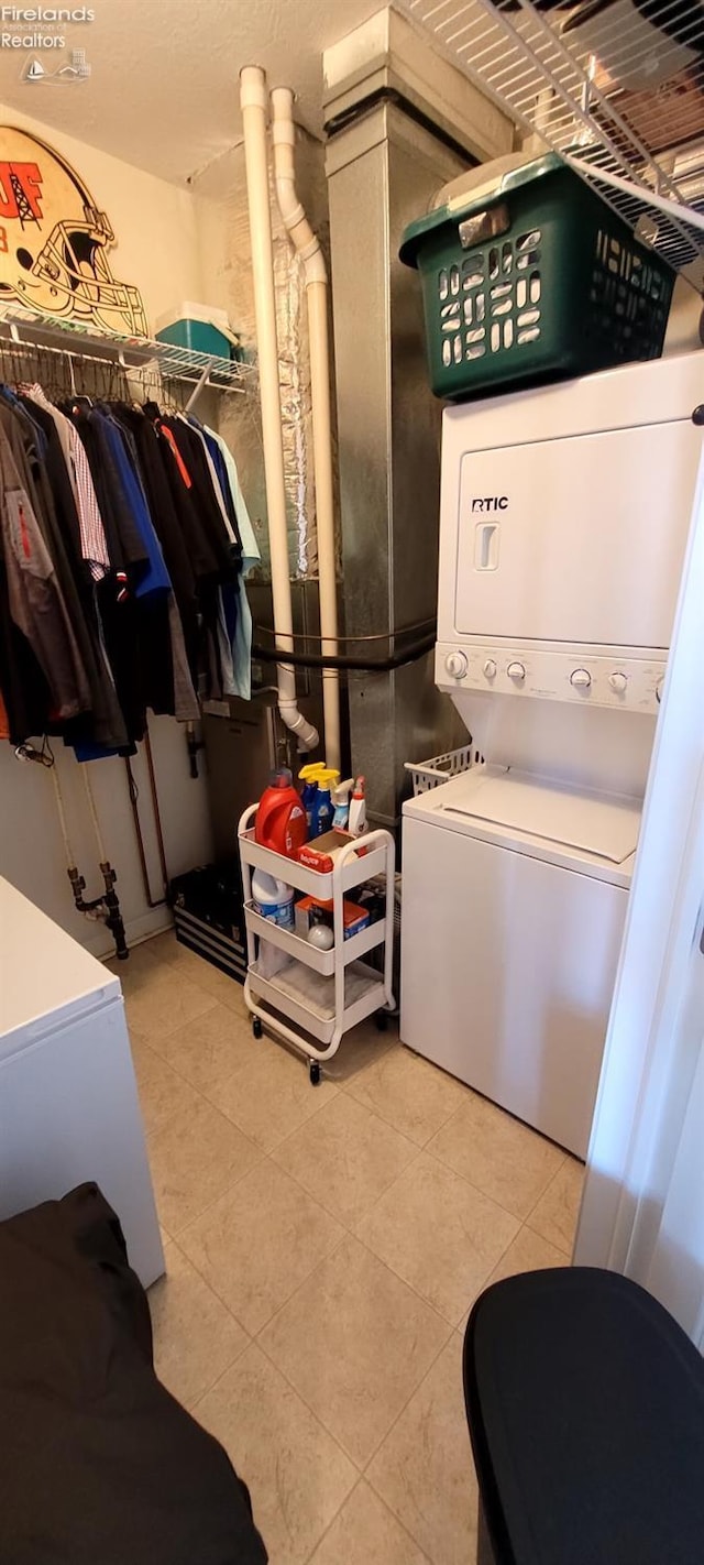 laundry room with tile patterned flooring and stacked washer / dryer