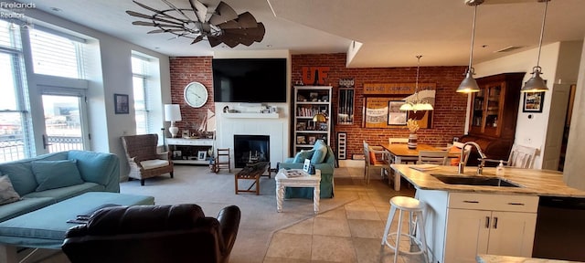 living area featuring visible vents, a ceiling fan, a glass covered fireplace, brick wall, and light tile patterned floors