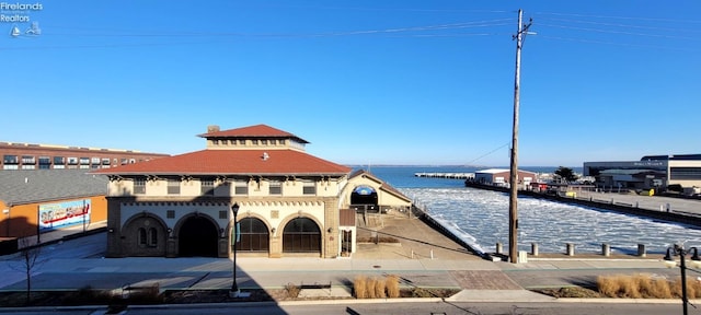 exterior space with a tile roof and a water view