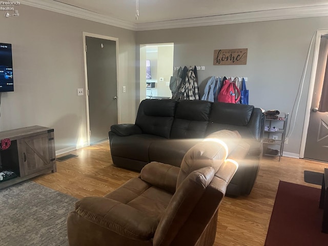 living area featuring visible vents, ornamental molding, baseboards, and wood finished floors