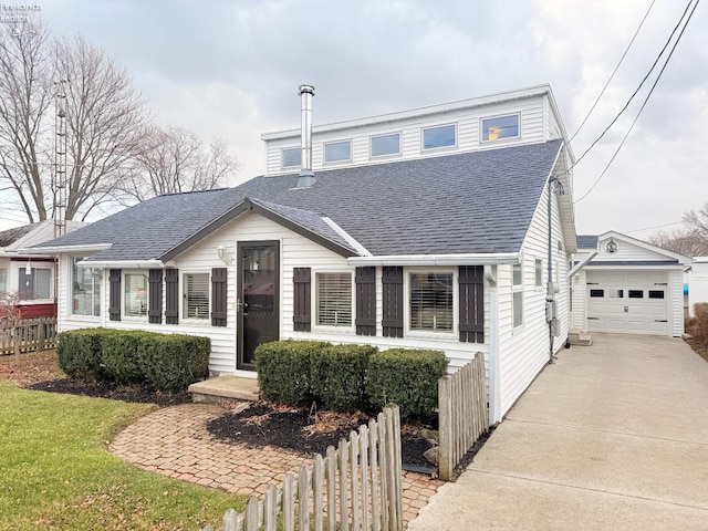 view of front of home with a shingled roof, fence, concrete driveway, a garage, and an outdoor structure