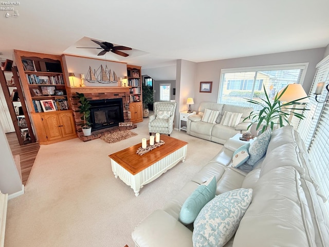 living area with a brick fireplace, ceiling fan, and carpet floors