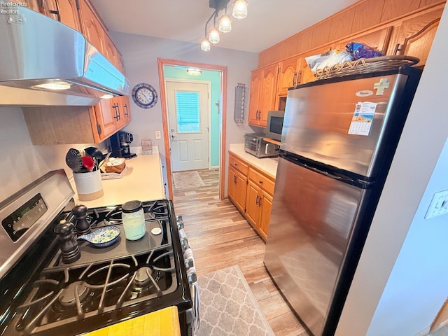 kitchen featuring under cabinet range hood, appliances with stainless steel finishes, light wood-type flooring, and light countertops