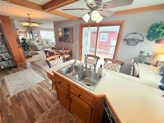 kitchen featuring brown cabinetry, dark wood-style floors, a sink, light countertops, and beamed ceiling