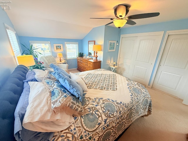 carpeted bedroom featuring a ceiling fan, lofted ceiling, and multiple closets