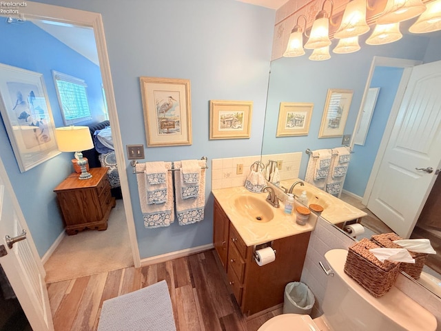 ensuite bathroom featuring vanity, wood finished floors, baseboards, toilet, and connected bathroom