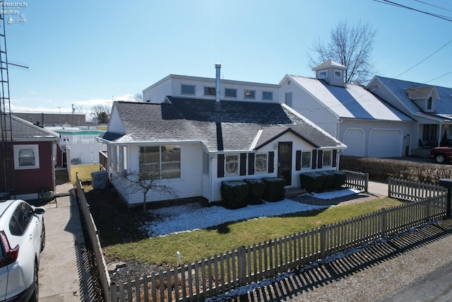 view of front of home featuring a front lawn, a garage, a fenced front yard, and roof with shingles