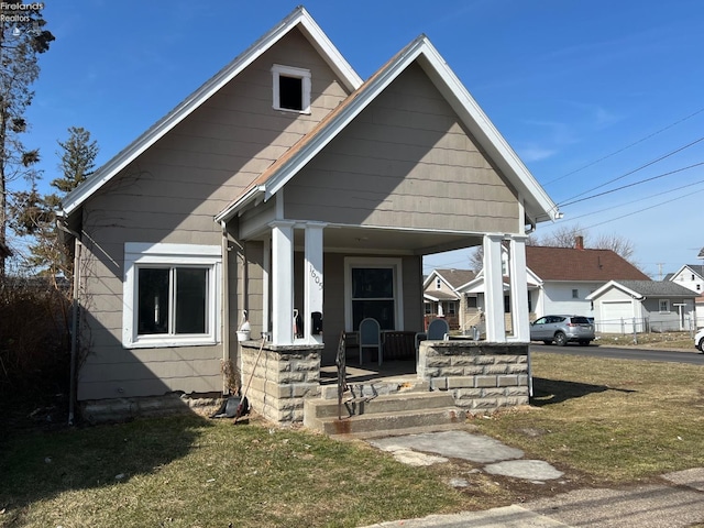 bungalow-style home with a front lawn and covered porch