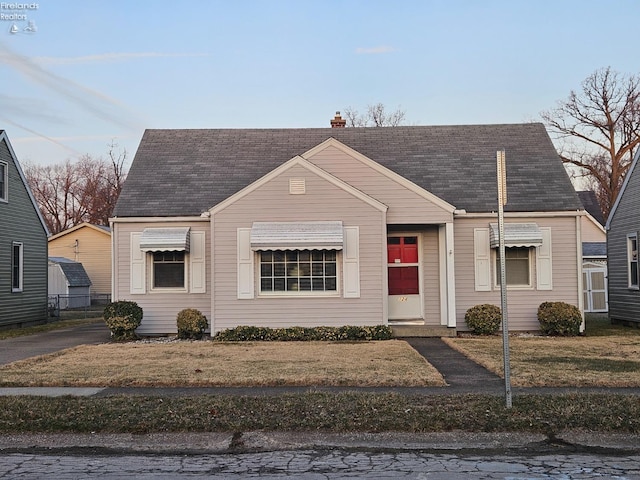 bungalow-style home with a chimney and roof with shingles