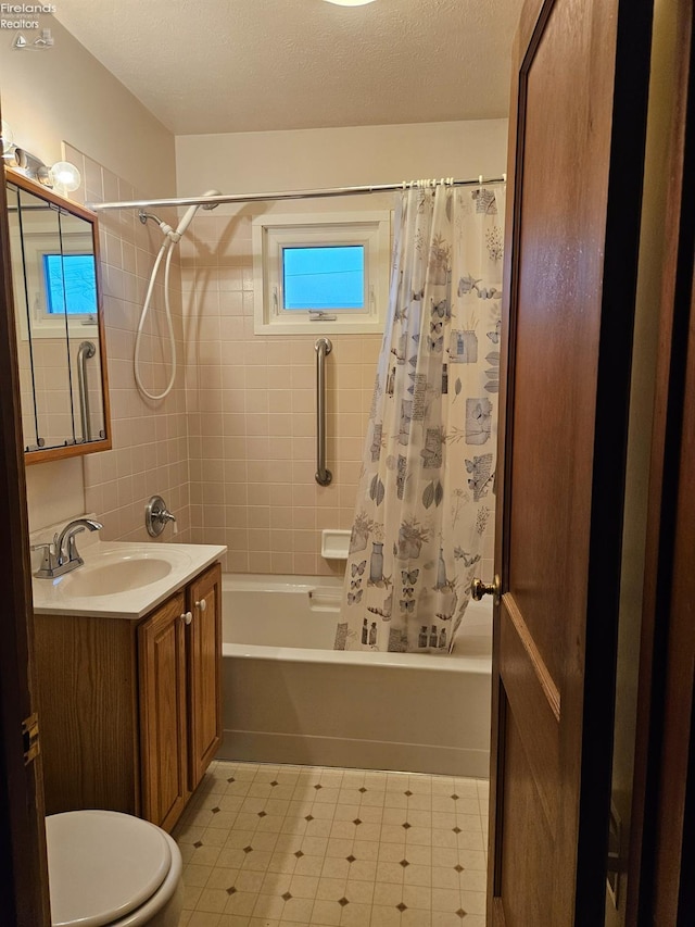 full bathroom featuring vanity, shower / bathtub combination with curtain, a textured ceiling, tile patterned floors, and toilet