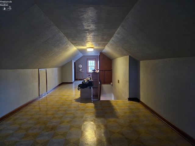 additional living space with tile patterned floors, baseboards, and lofted ceiling